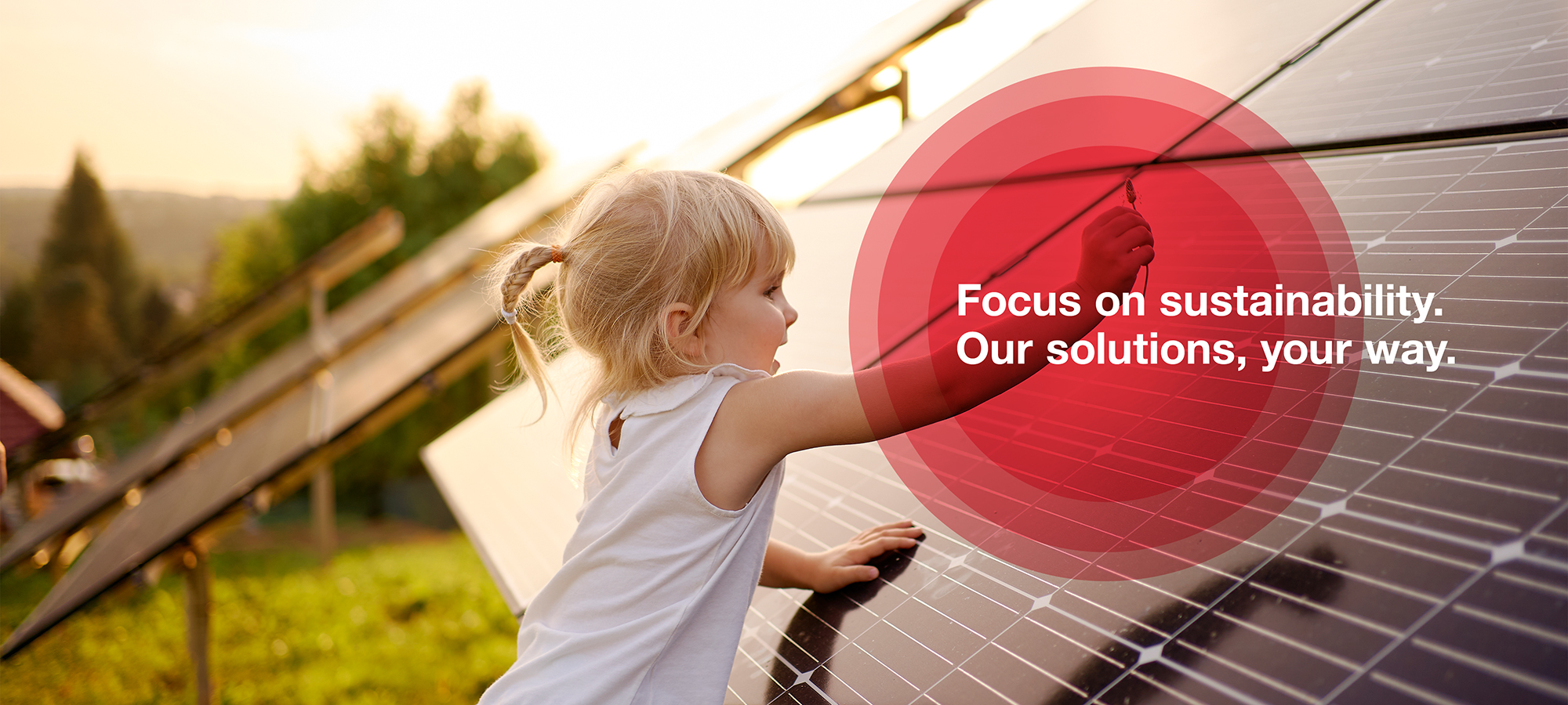 A photograph of a little girl who plays in the nature surrounded by solar panels. 